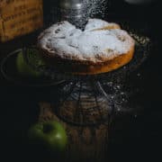 a cake on a cake stand being dusted with powdered sugar