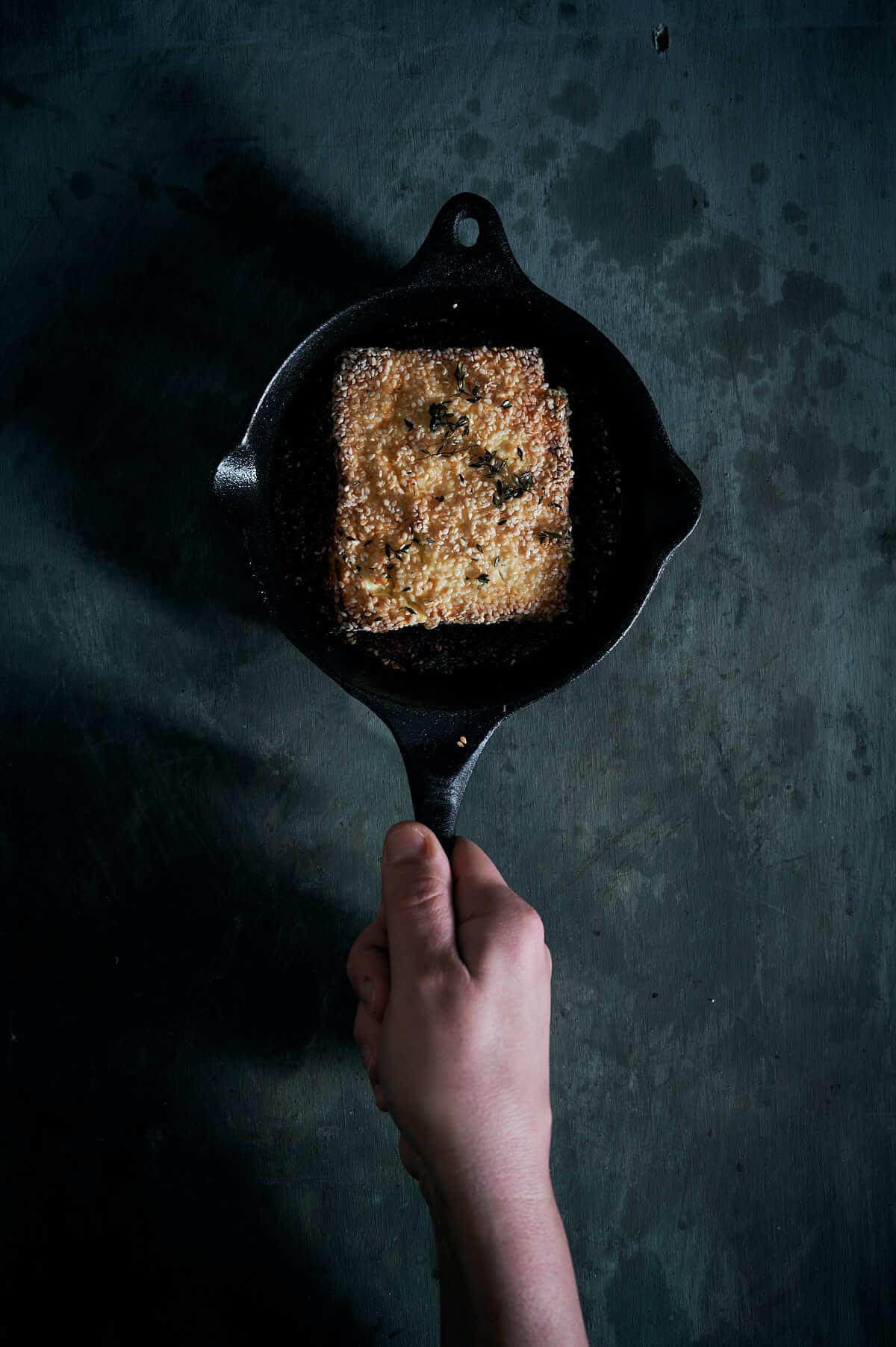 a hand holding a cast iron pan