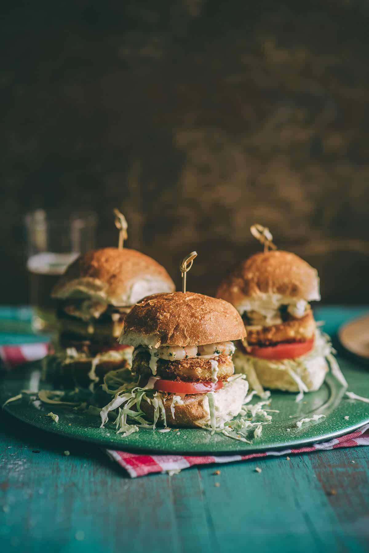 three burgers on a green plate on a table