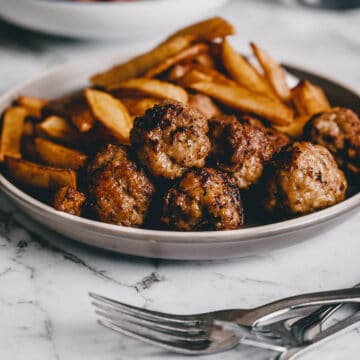 close up of fried meatballs with french fries in the background