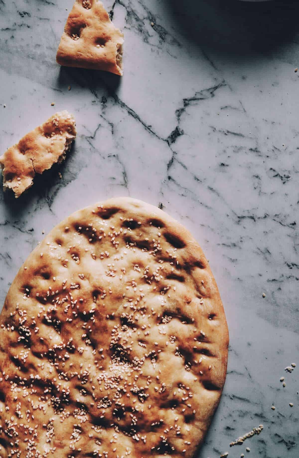 freshly baked flatbread on a table covered in sesame seeds