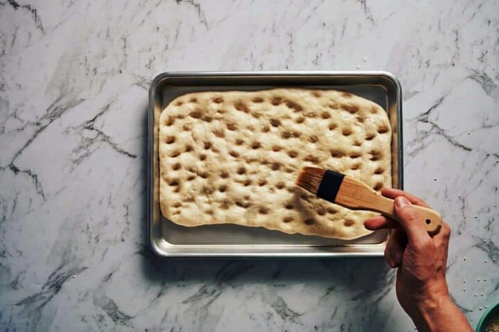 brushing olive oil over a flatbread before it gets baked