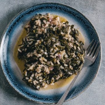 a blue and white late filled with a greek spinach and rice dish known as spanakorizo.