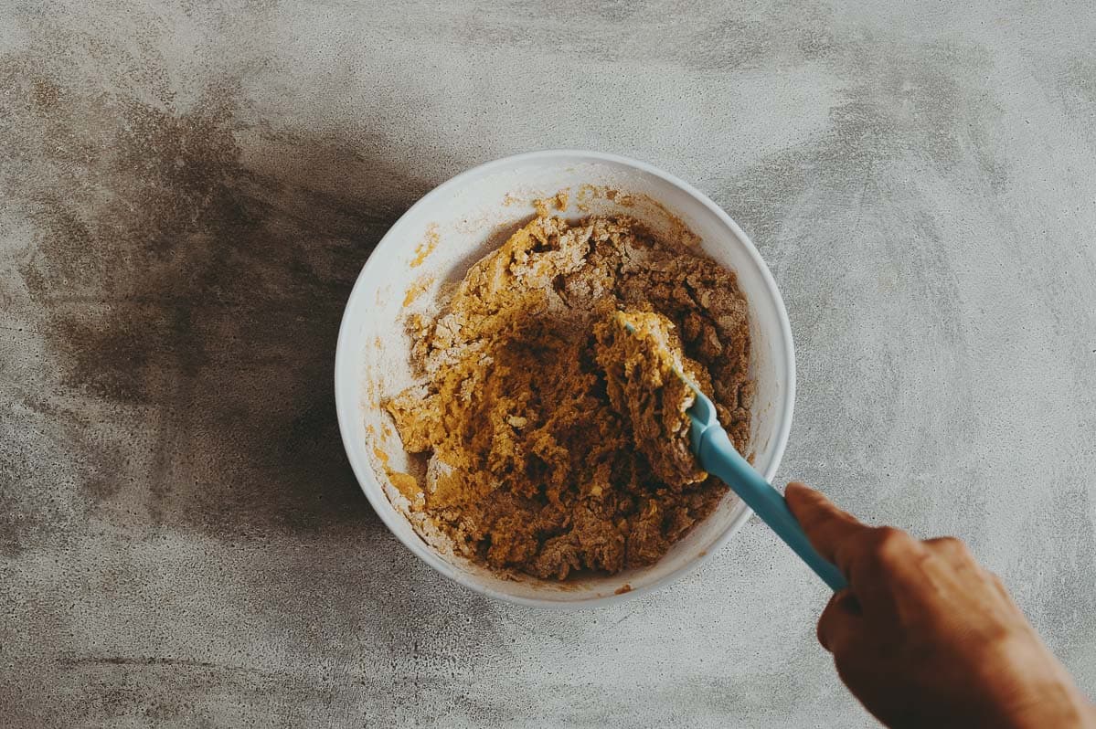 mixing pumpkin scone dough with a spatula in a bowl.
