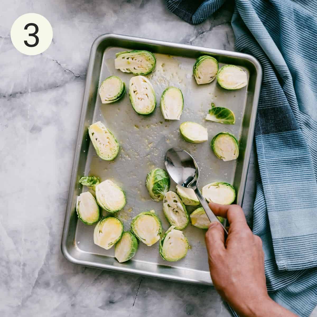 tossing halved brussels sprouts with olive oil, salt and pepper on a roasting pan.