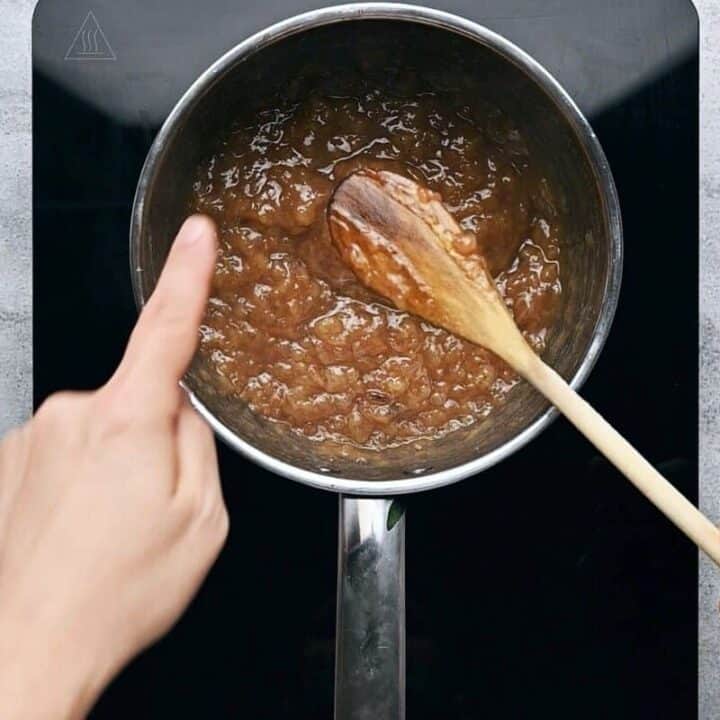 a finger wiping the back of a spoon to determine the thickness of banana jam