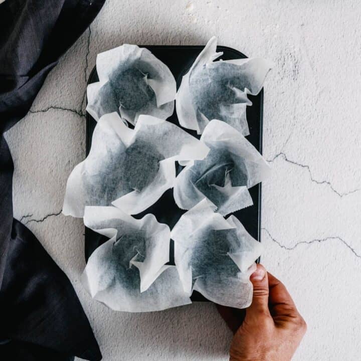 lining a muffin tray with muffin liners made from parchment paper.