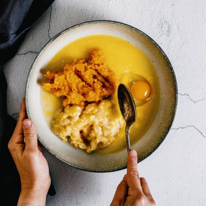 combing mashed banana, pumpkin puree and egg in a bowl.