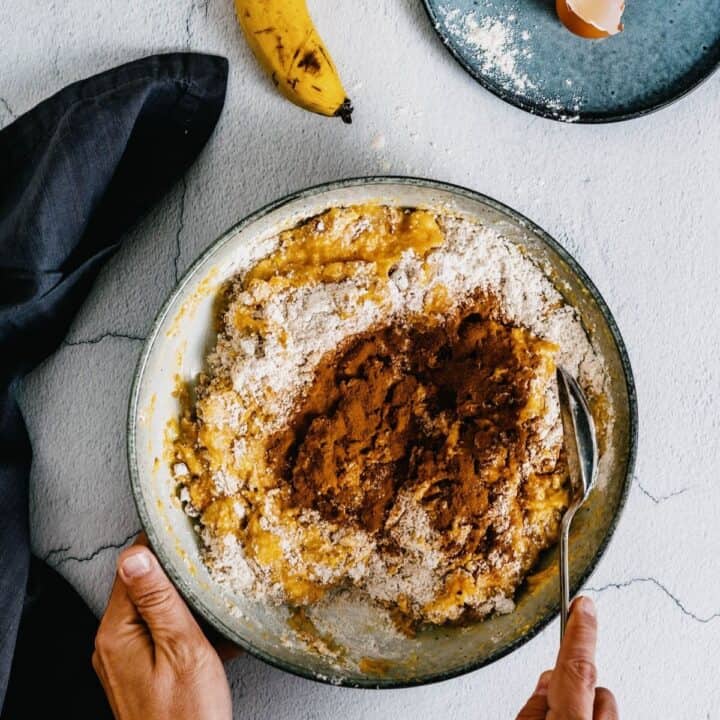 stirring together wet and dry ingredients for pumpkin banana muffins.