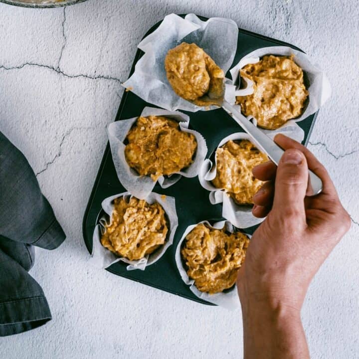 filling liners in a baking tray with muffin batter.