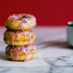 3 strawberry frosted doughnuts stacked on top of each other.