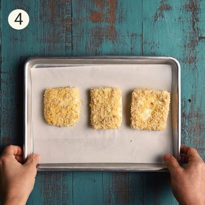 3 pieces of crumbed cheese on a lined baking tray.