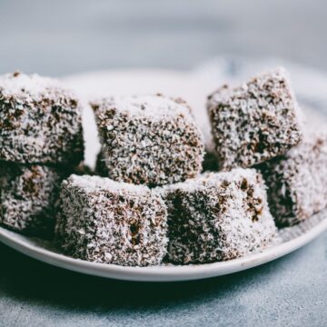 gluten-free lamingtons stacked on a white plate.