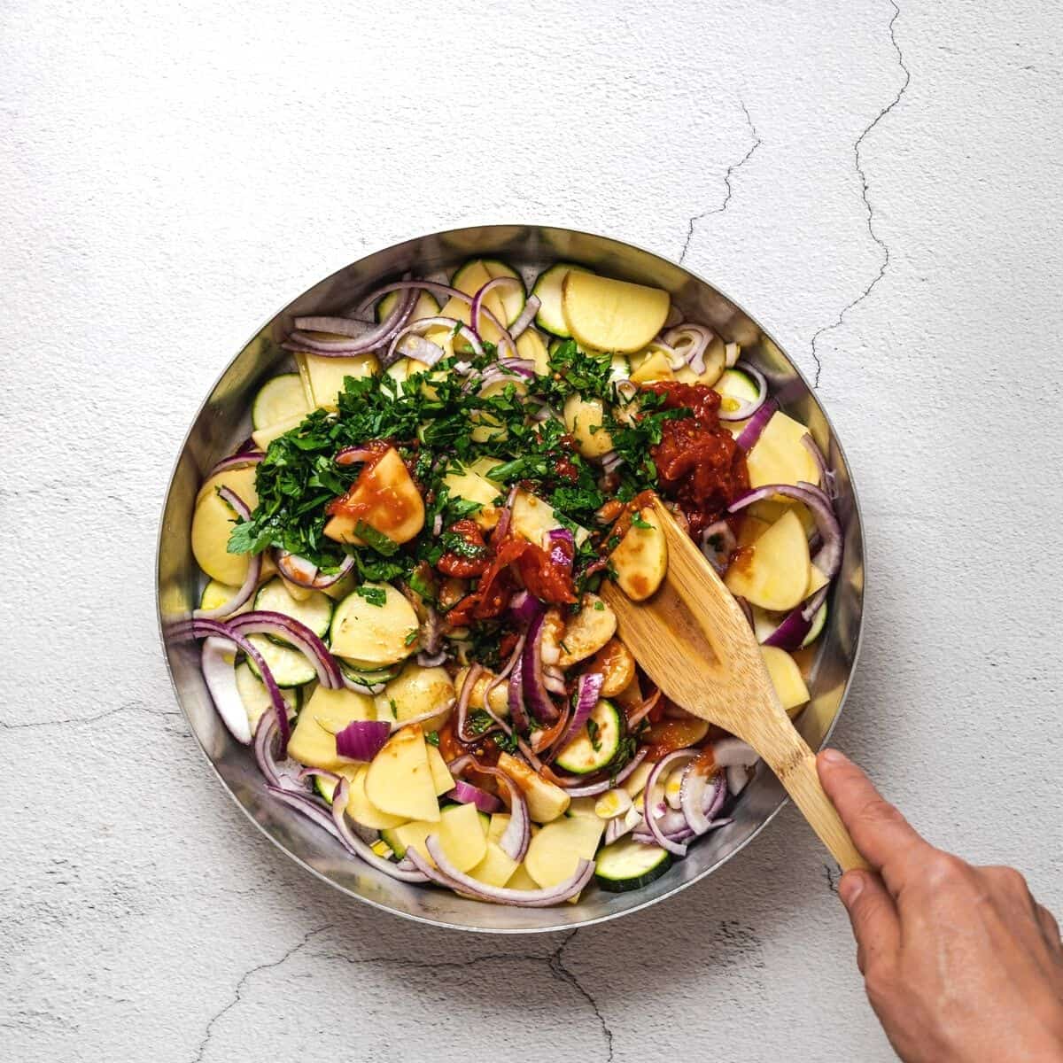 stirring chopped vegetables in a round baking dish.