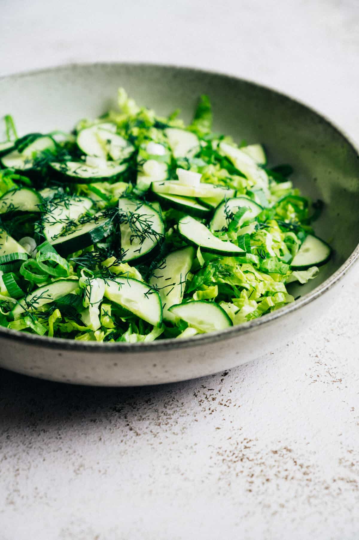 a large bowl of Greek lettuce salad on a rustic table.