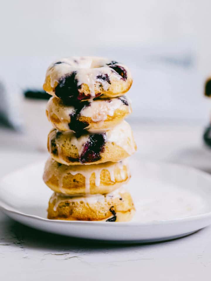 a white plate with a stack of 5 blueberry cake donuts.