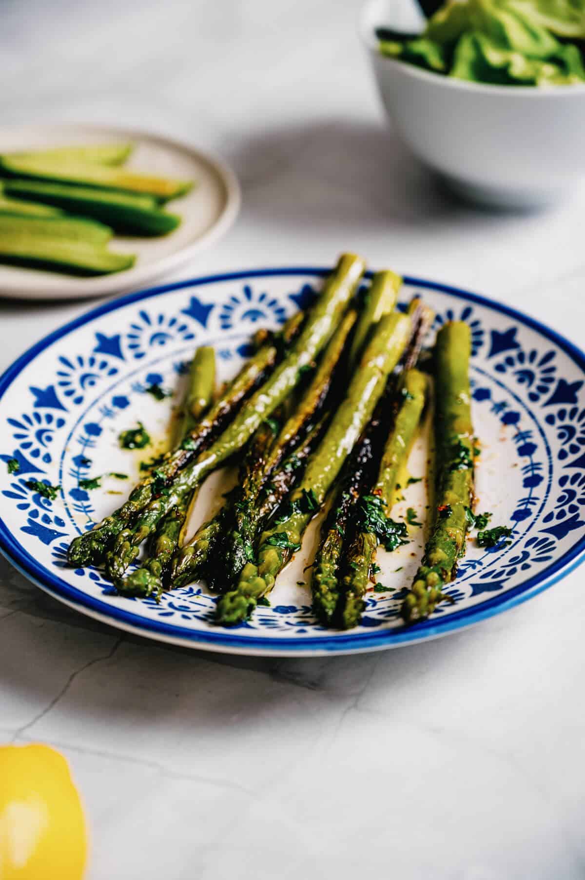 a white and blue plate filled with grilled asparagus.