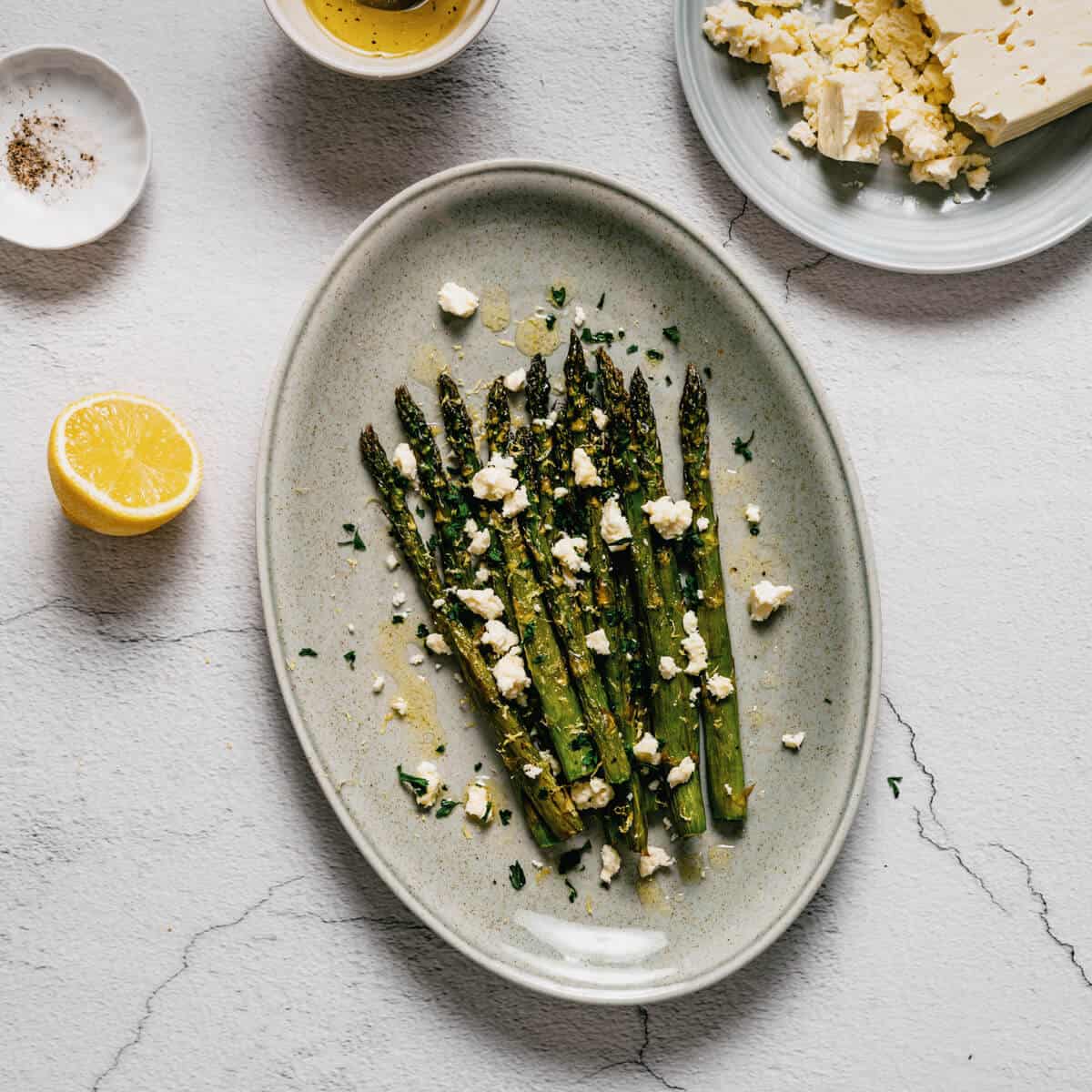a platter of asparagus topped with crumbled feta cheese.