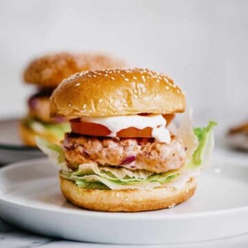 a grilled salmon burger on a white plate.