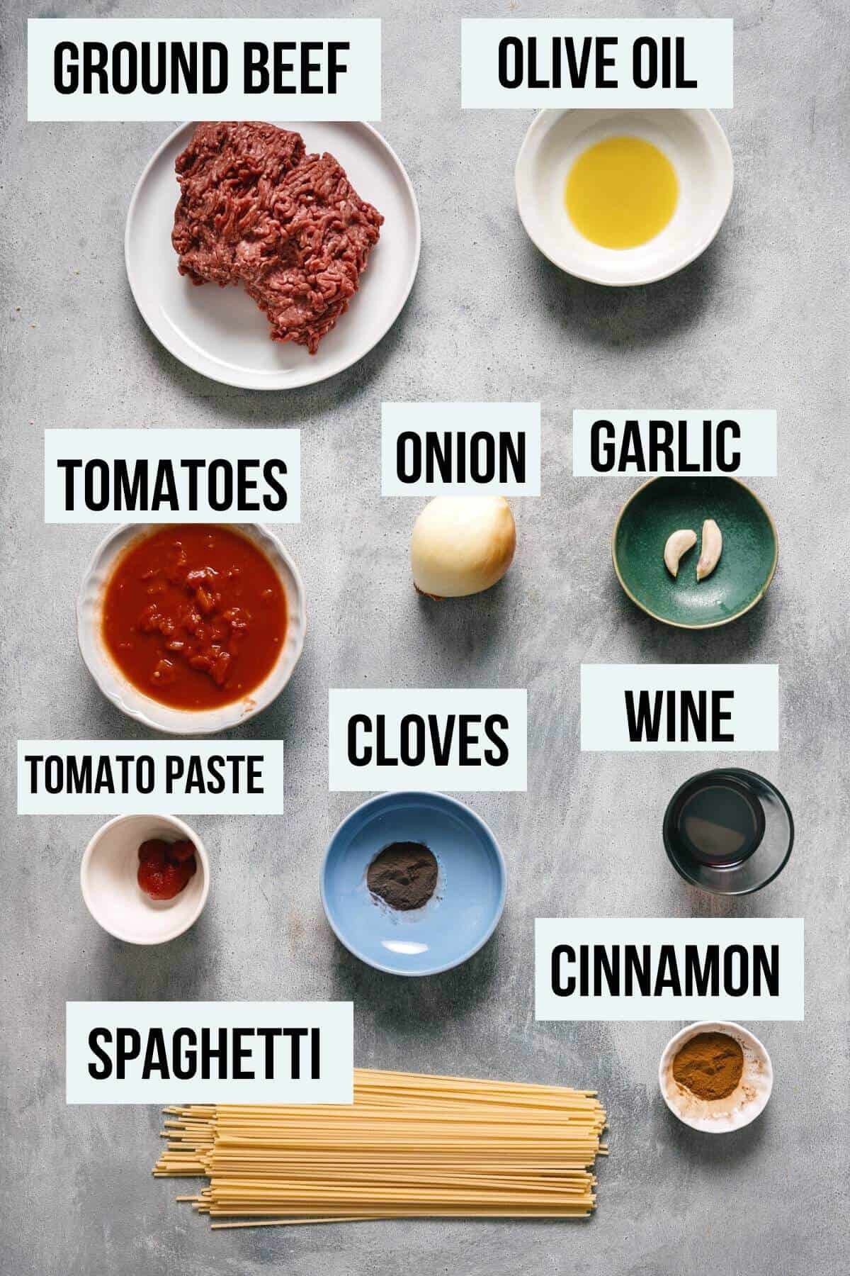 ingredients for makaronia me kima (greek spaghetti)on a grey table.