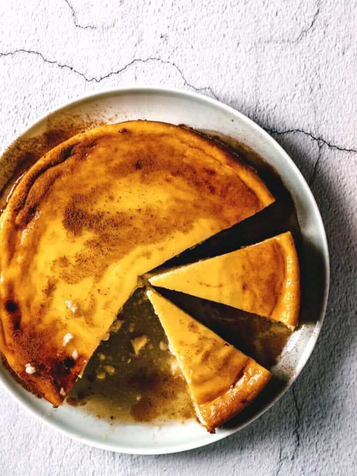 a greek cheesecake on a plate drizzled with honey.