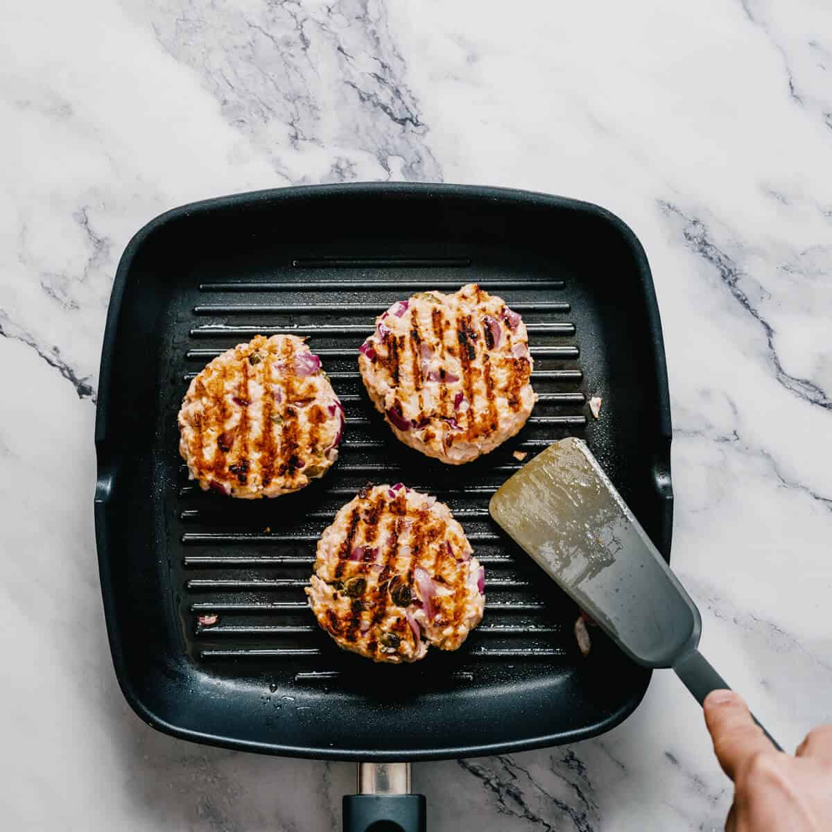 cooking salmon burgers in a grill pan.