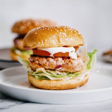 a grilled salmon burger on a white plate.