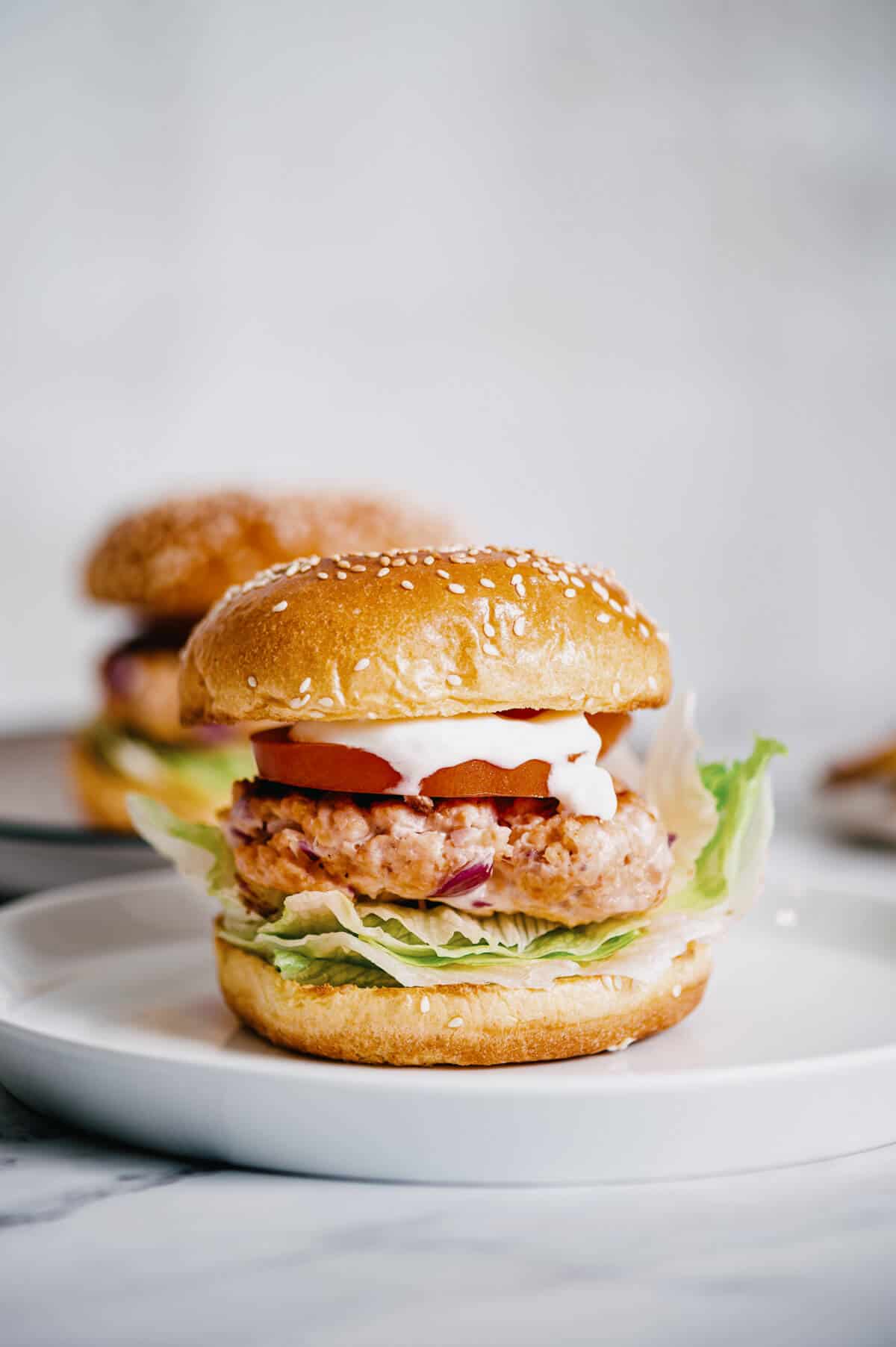 a grilled salmon burger on a white plate.