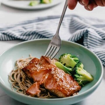 a fork piercing a piece of salmon cooked in an air fryer.