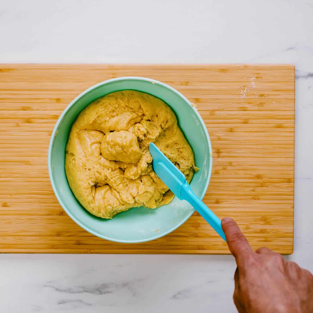 stirring cookie dough in a green bowl.