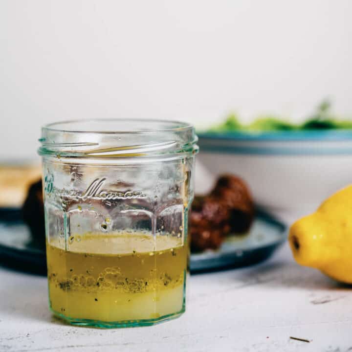 a glass jar filled with Greek olive oil and lemon sauce.