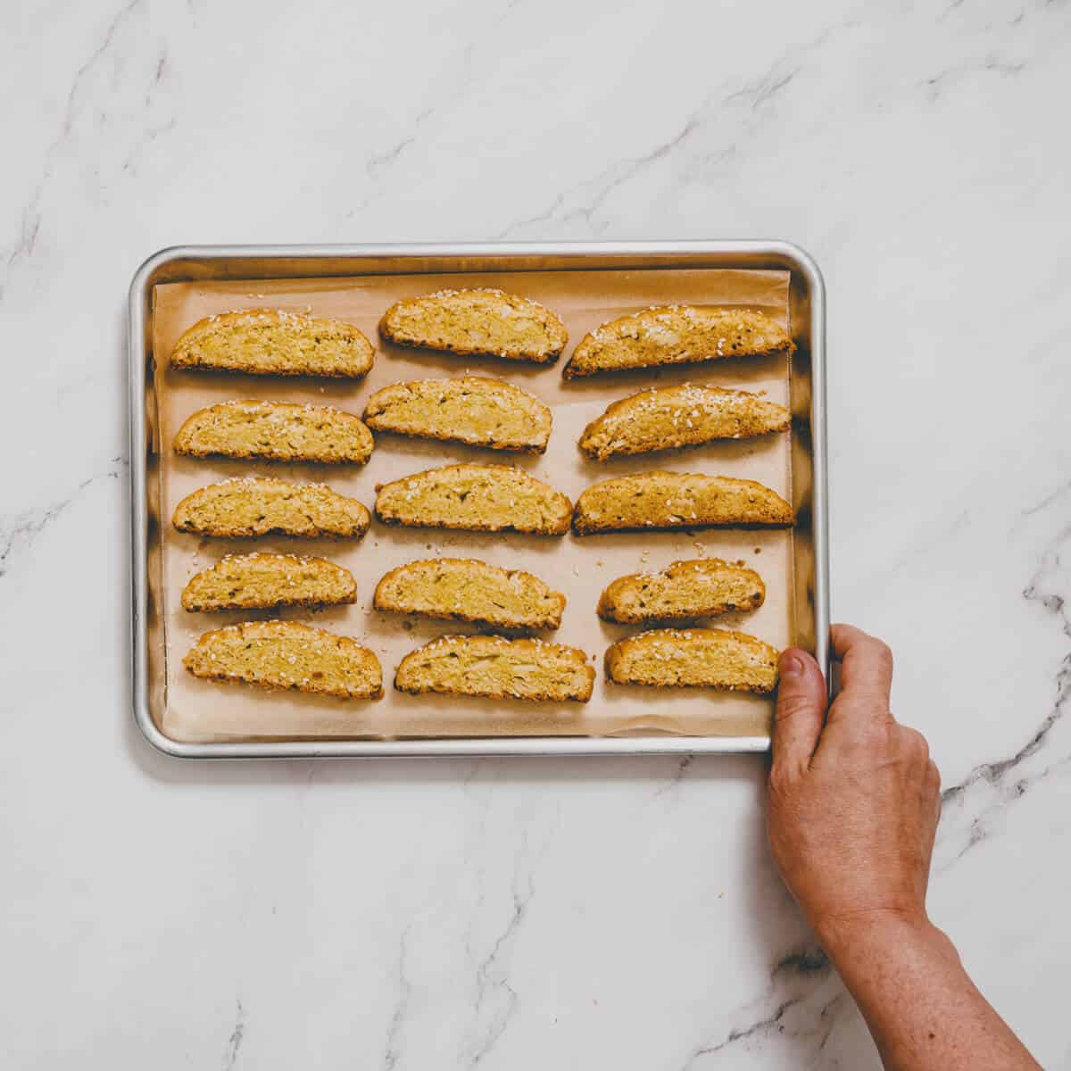 Greek biscotti being baked on a parchment lined baking tray.