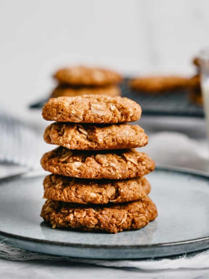 a stack of 5 Anzac biscuits on a grey plate.