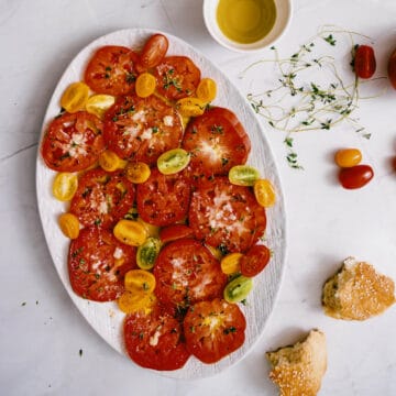 an heirloom tomato salad presented on a large white platter.
