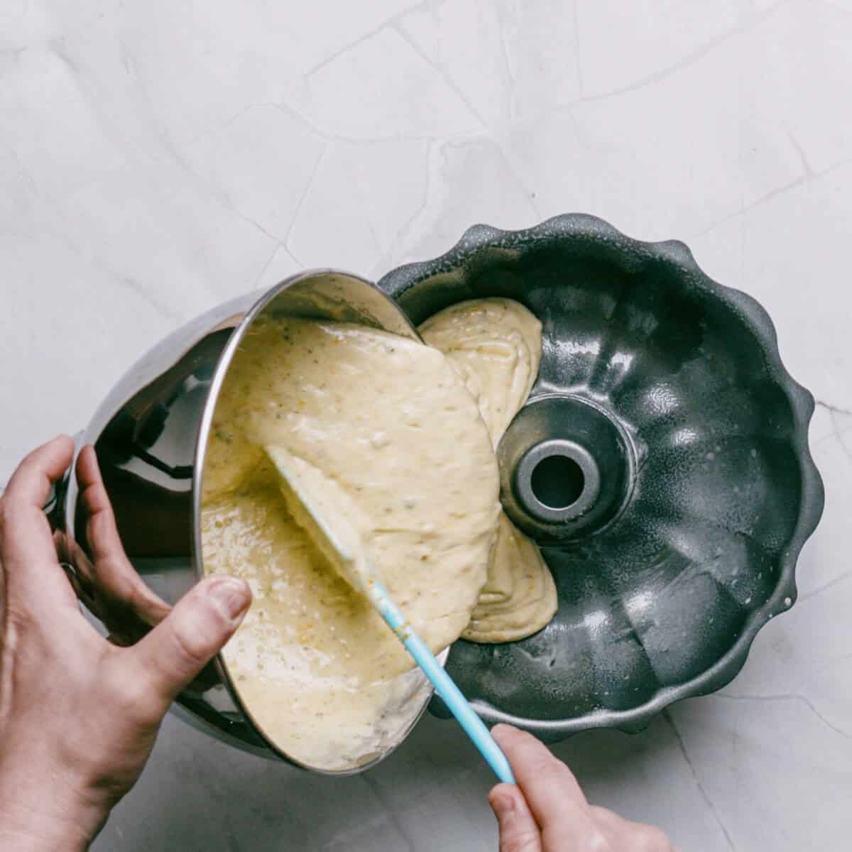 pouring cake batter into a fluted bundt pan.