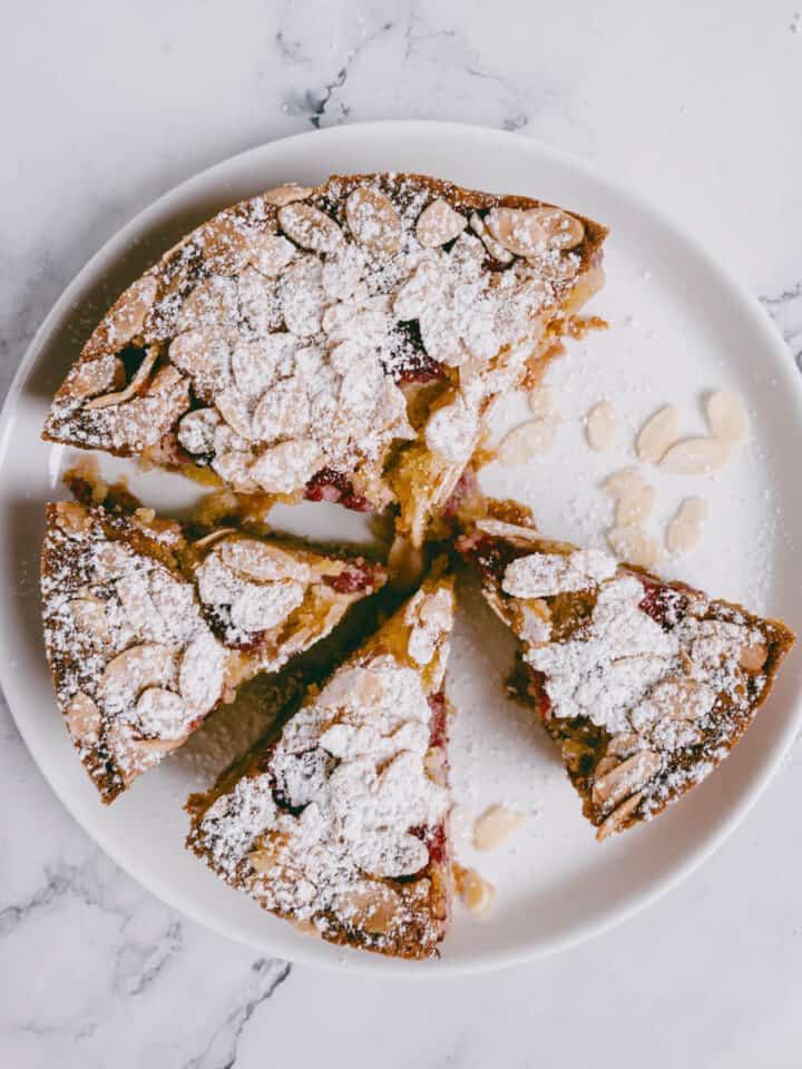 sliced raspberry almond cake on a white plate.