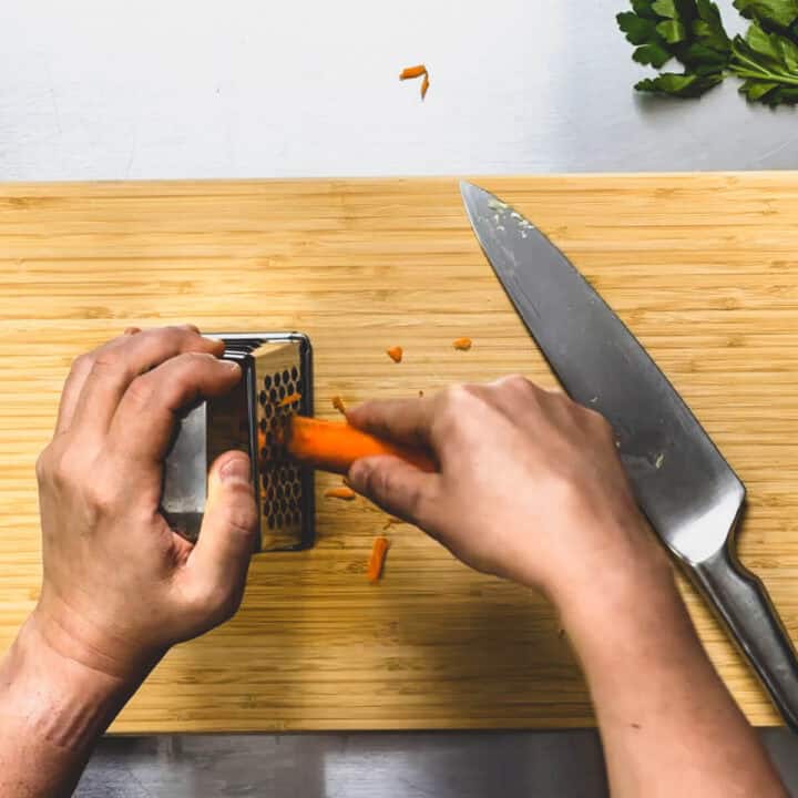 a carrot being grated with a box grater.