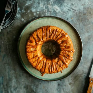 an apple cinnamon teacake on a dark surface on a green plate.