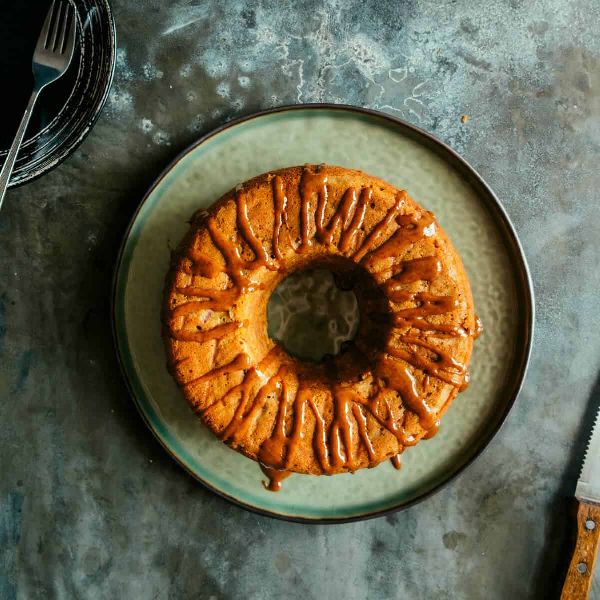an apple cinnamon teacake on a dark surface on a green plate.