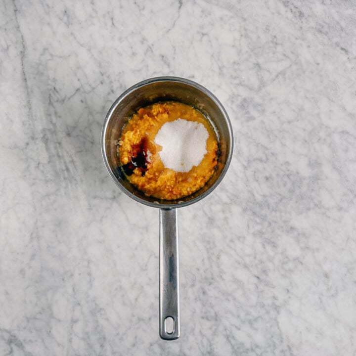 processed mandarins and sugar in a stainless steel saucepan.