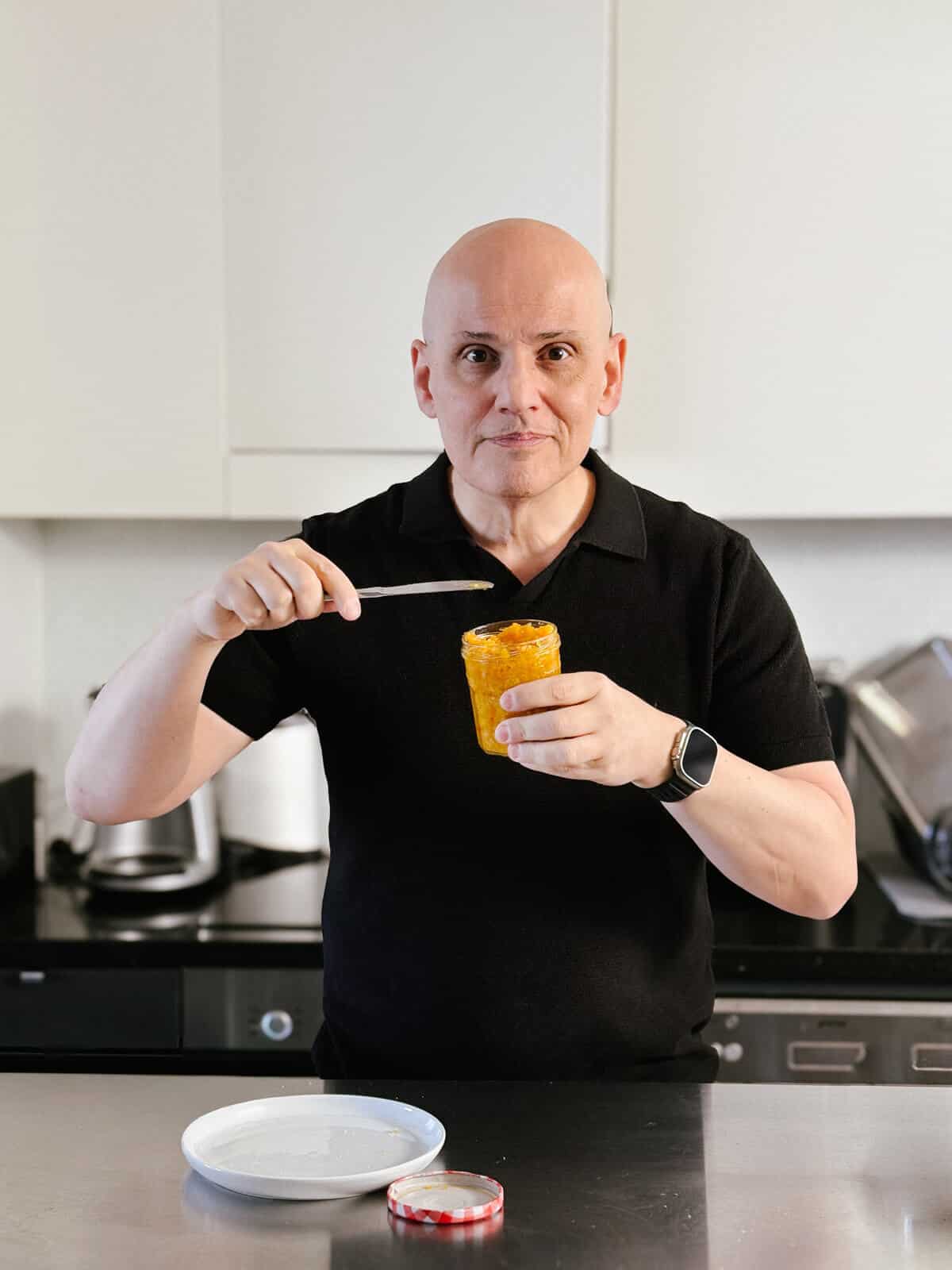 the blogger at souvlaki for the soul holding a jar of homemade mandarin jam.