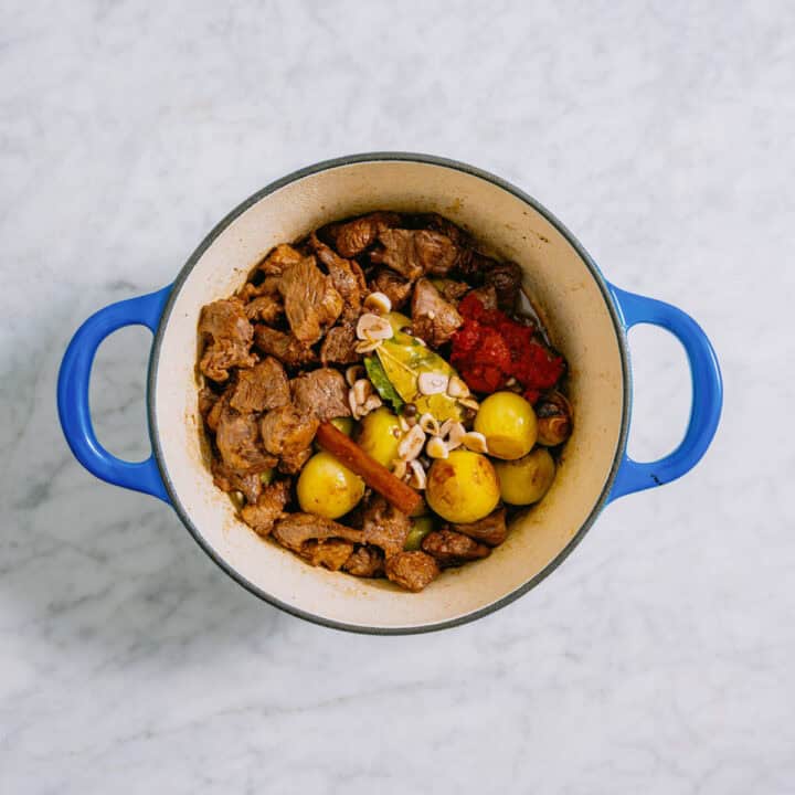 greek beef stew in a blue pot cooking.