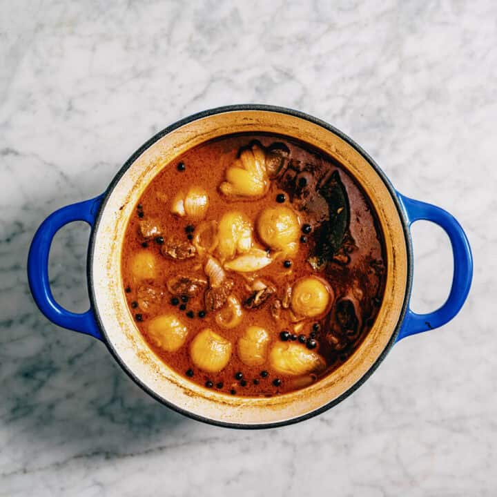 Greek beef stew finished and looking glossy and rich in a blue pot.