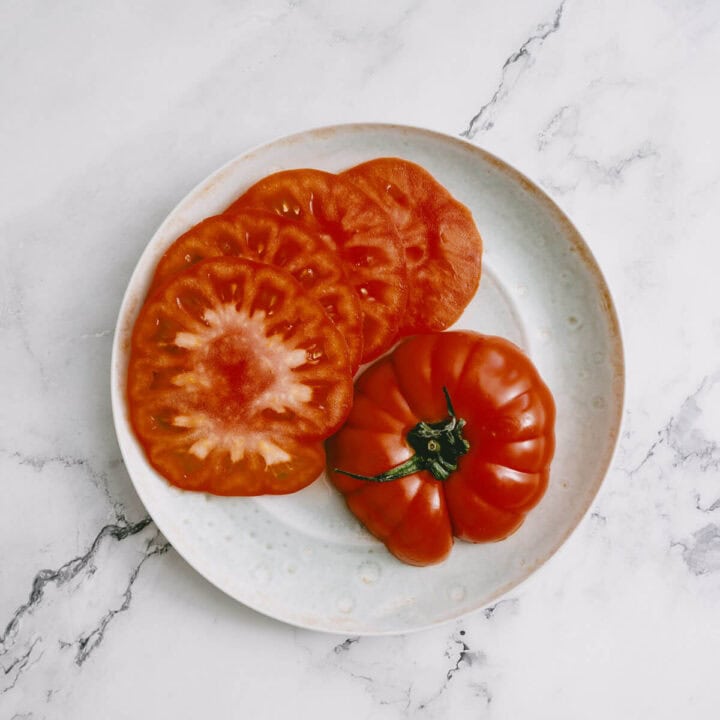 Sliced heirloom tomatoes on a plate, ready for making halloumi salad.
