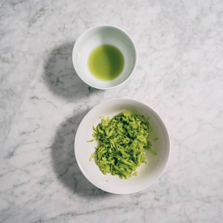 Grated cucumber in a bowl with drained cucumber water for tzatziki.