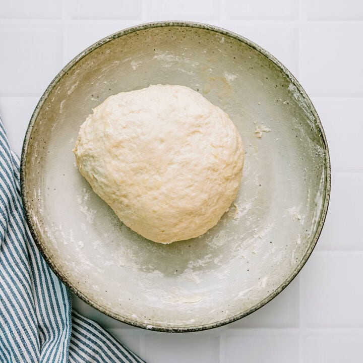 Soft pita dough resting in a bowl after kneading.