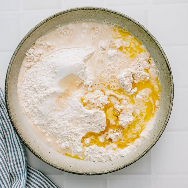 Flour, yeast, olive oil and water being combined in a ceramic bowl to make pita dough.
