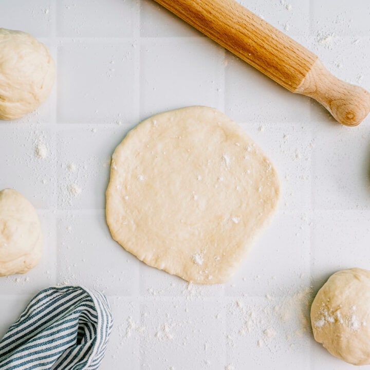 Greek pita dough rolled into a round shape ready for cooking.