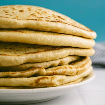 Close-up of Greek pita bread with soft layers and golden surface.