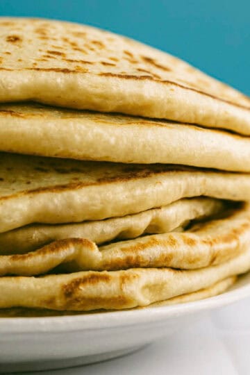 Close-up of Greek pita bread with soft layers and golden surface.